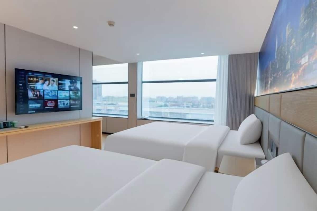 Habitación de hotel con dos camas, televisión, vistas a la ciudad y un cuadro en la pared.
