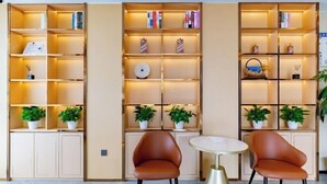A modern interior with three bookshelves, two brown chairs, and a small round table. - Huizhou galston hotel (Huizhou)