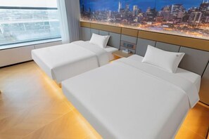 A hotel room with two beds, a nightstand, a cityscape view, and a window with curtains.