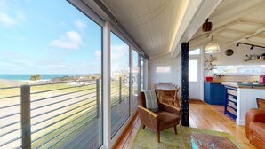 A spacious room with large windows overlooking a beach, a cozy seating area, and a modern kitchen. - C24 Rosemary, Riviere Towans (Hayle)