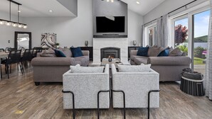 A modern living room with a fireplace, two sofas, a coffee table, and a TV mounted on the wall. - Candlewood Lakefront 3bd/ 2 bath house w/ 180 degree views! (Danbury)