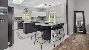 A modern kitchen with a central island, bar stools, and a ceiling fan. - Candlewood Lakefront 3bd/ 2 bath house w/ 180 degree views! (Danbury)