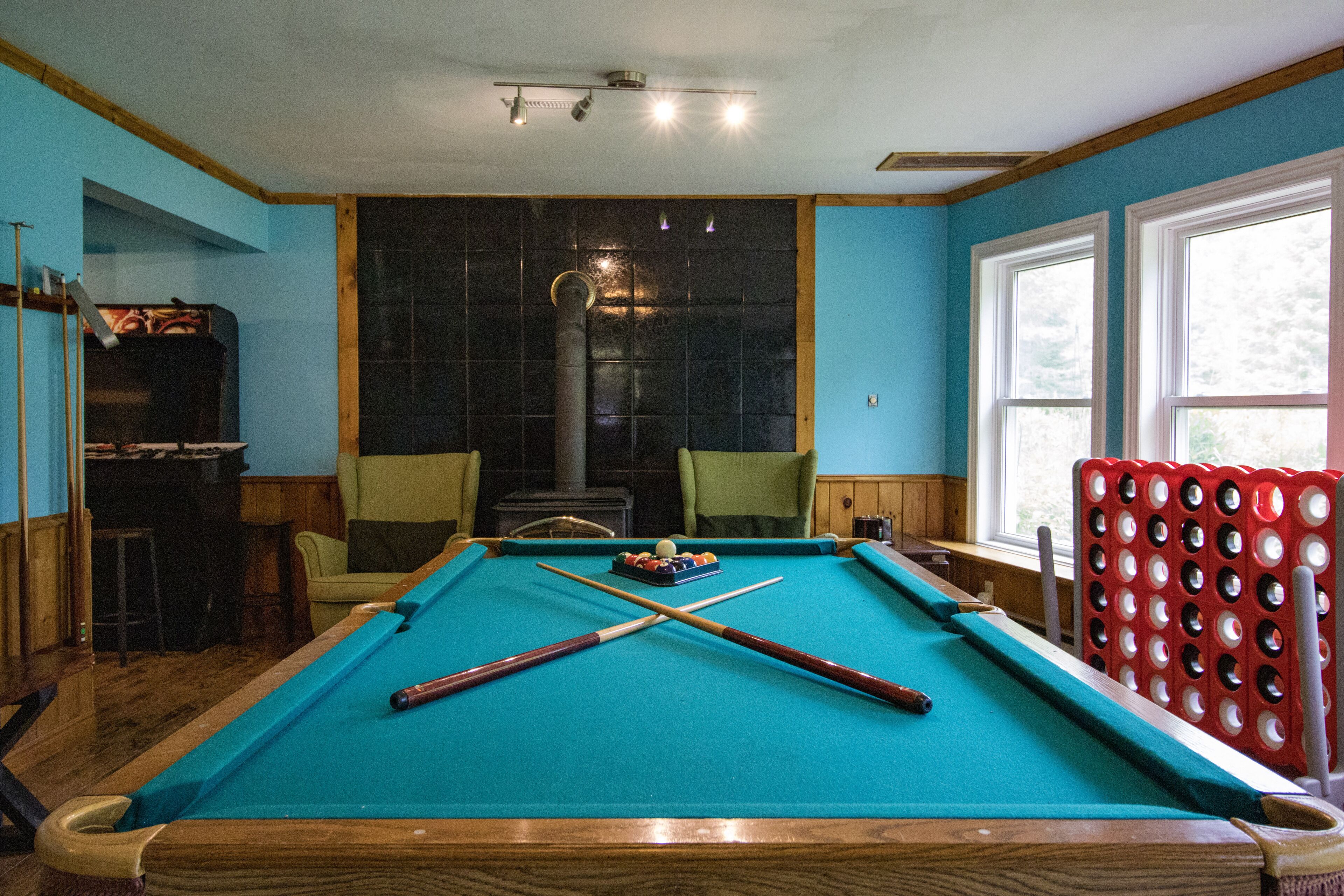 Een pooltafel met een rode veiligheidsband, een bar met krukken en een open haard.