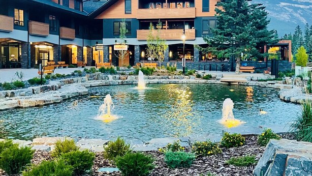 A hotel with a pool, outdoor seating, and mountain views. - Iron Mountain Penthouse - World-class Luxury in the Rocky Mountains (Canmore)