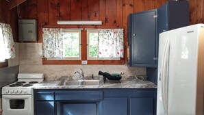 Eine kleine Küche mit Holzwänden, einem weißen Herd, einer Spüle und einem Samsung-Kühlschrank.
