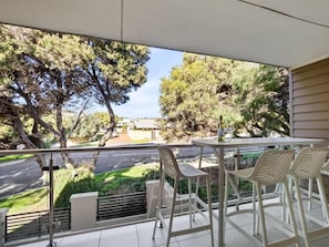A balcony with a table and chairs, overlooking a street and greenery. - Surfside 1—An Unforgettable Yallingup Experience (Yallingup)