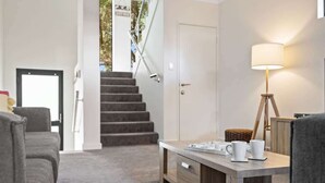 A modern living room with a staircase, a coffee table, and a lamp. - Surfside 1—An Unforgettable Yallingup Experience (Yallingup)