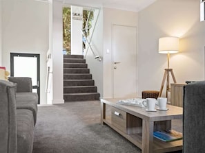 Ein modernes Wohnzimmer mit Treppe, Couchtisch und Lampe.