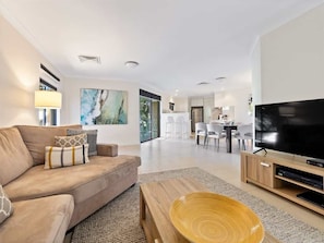 Ein modernes Wohnzimmer mit Sofa, Couchtisch, Fernseher und Essbereich.