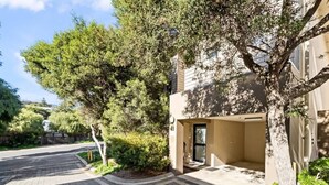 A residential area with a paved driveway, a house with a visible entrance, and surrounding greenery. - Surfside 1—An Unforgettable Yallingup Experience (Yallingup)