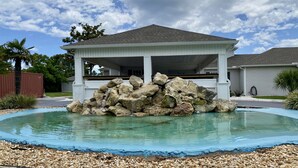 Espaço ao ar livre coberto, com formação rochosa e piscina.