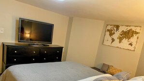 A hotel room with a bed, a dresser, a television, and a world map on the wall.