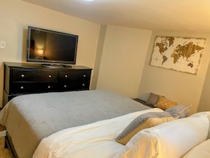 A hotel room with a bed, a dresser, a television, and a world map on the wall.
