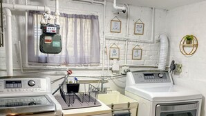 A compact laundry room with a washing machine, dryer, and a utility meter on the wall.