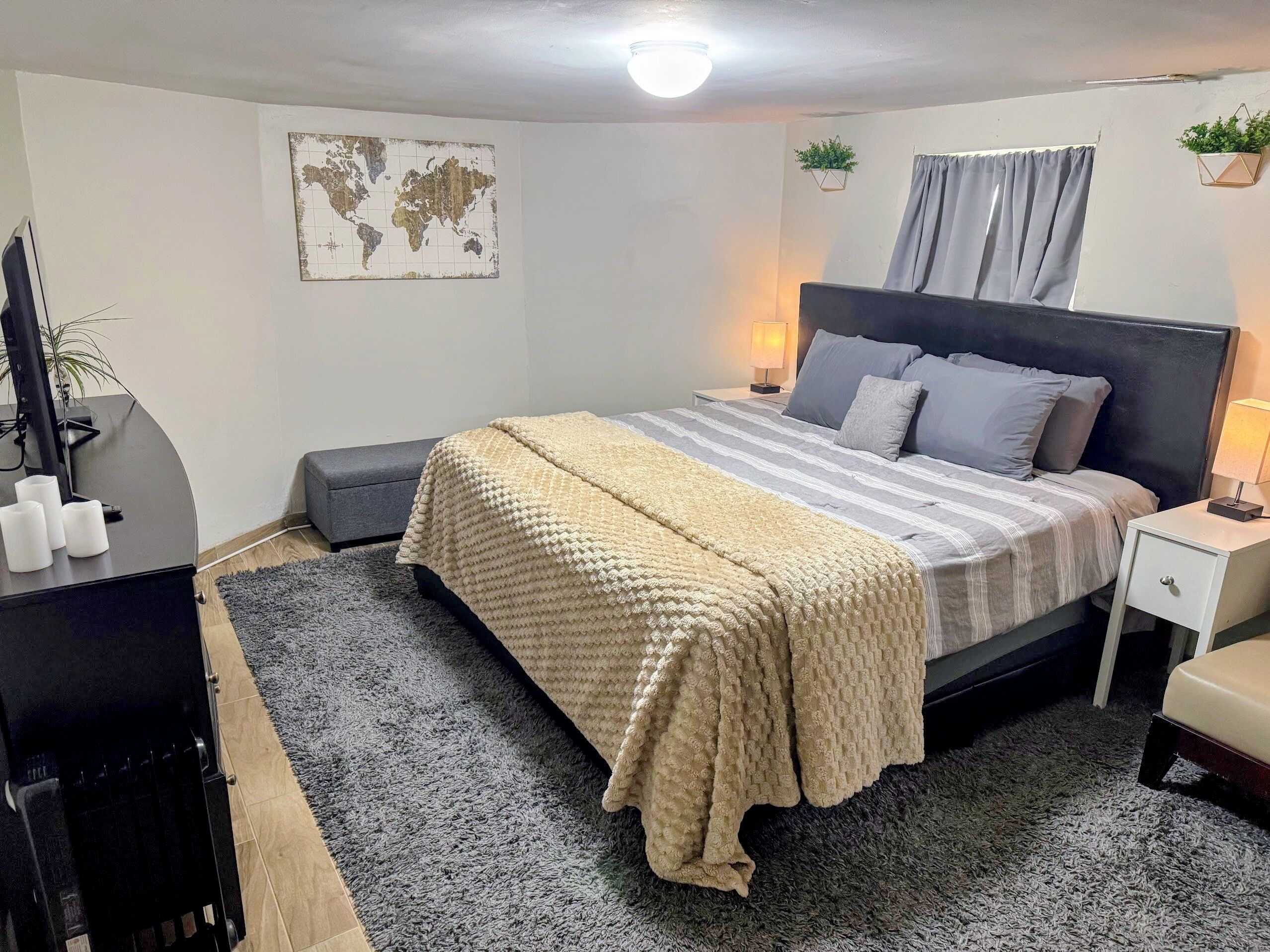 A neatly arranged bedroom with a bed, bedside tables, a desk, and a world map on the wall.
