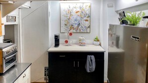 A modern kitchen with a built-in oven, a coffee maker, a sink, and a refrigerator.