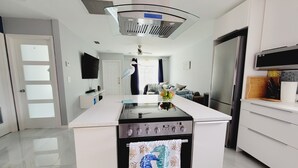 Una cocina moderna con una isla central, electrodomésticos de acero inoxidable y encimera blanca.