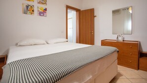 Een slaapkamer met een bed, een dressoir, een spiegel en abstracte kunst aan de muur.