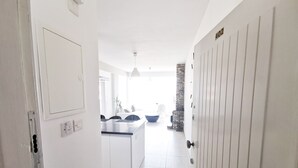 A modern kitchen with white cabinets, a central island, and a dining area with chairs. - Mackenzie Seaview Paradise (Larnaca)