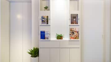 A modern, white interior with built-in shelving displaying books, plants, and decorative items.