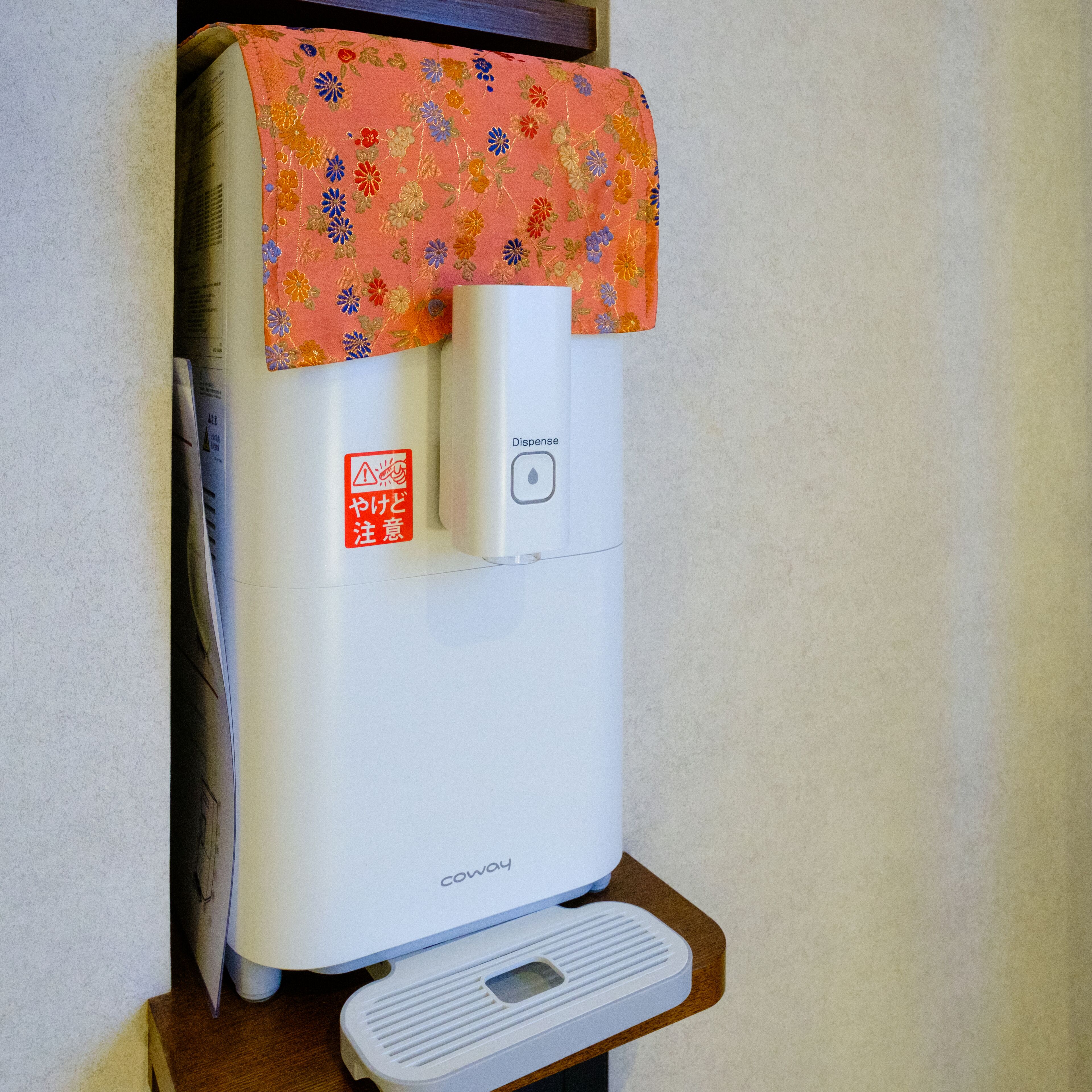 A water dispenser with a floral cover and a warning label.