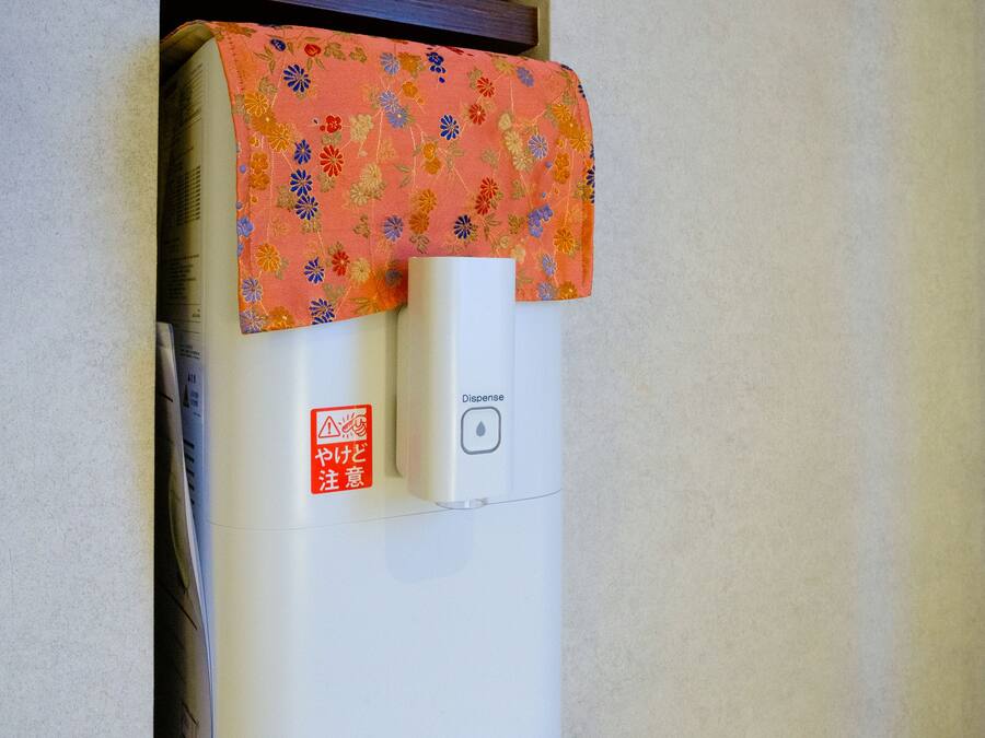 Un dispensador de agua con una cubierta floral y una etiqueta de advertencia.