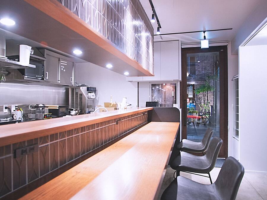 Una cocina moderna con electrodomésticos de acero inoxidable, encimera de madera y zona de estar con sillas.