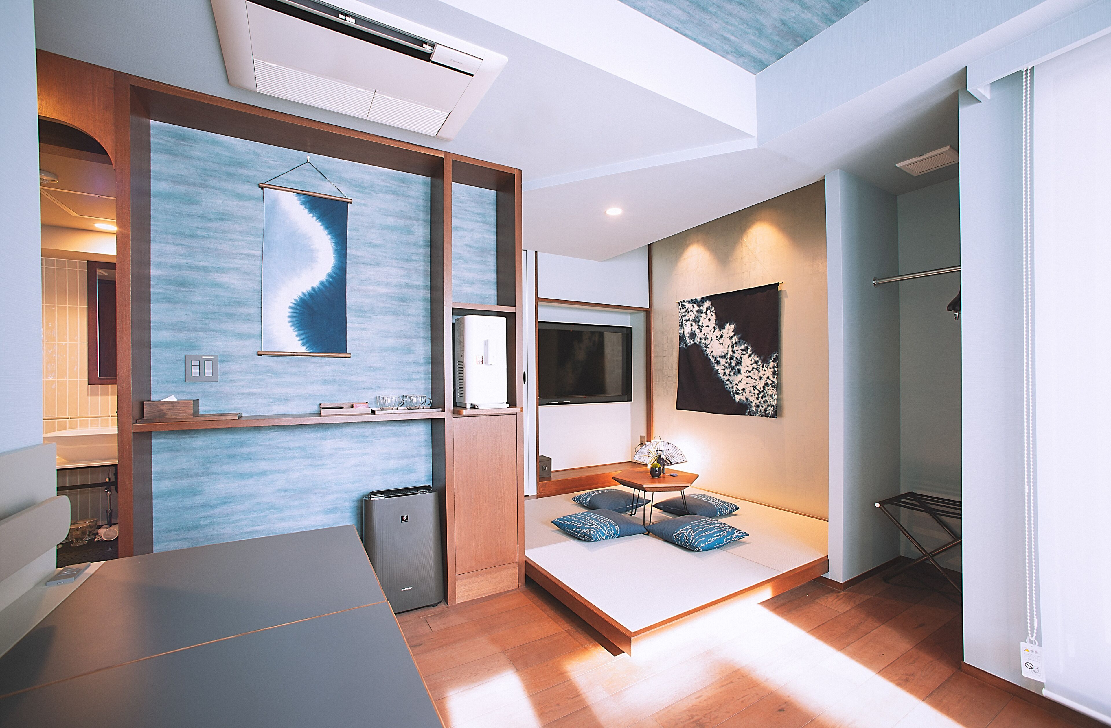 Une chambre d’hôtel moderne équipée d’un lit, d’une table de chevet, d’œuvres d’art et d’un système de climatisation intégré.