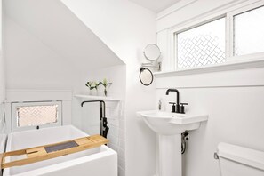 Un baño moderno con bañera, lavamanos y ventana.