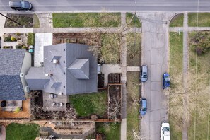 Vista aérea de una zona residencial con una casa, un camino de entrada y coches aparcados.