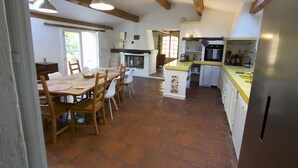 Een ruime keuken met een centraal kookeiland, een houten eettafel en stoelen.