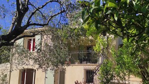 Een huis met een balkon, een trap en een tuin met tuinmeubilair.