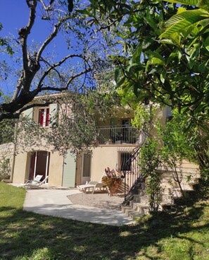 Une maison dotée d’un balcon, d’un escalier et d’un jardin aménagé avec du mobilier d’extérieur.