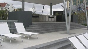 An outdoor seating area with white lounge chairs and a covered patio. - Sky Point Tower - Private Apartments (Surfers Paradise)