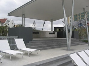 An outdoor seating area with white lounge chairs and a covered patio. - Sky Point Tower - Private Apartments (Surfers Paradise)