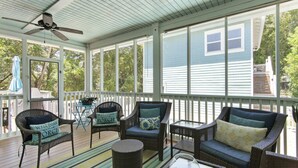 A covered porch with wicker furniture, a ceiling fan, and a view of a house. - Koko Palms Home with Pool, Carriage House & Cart (Destin)