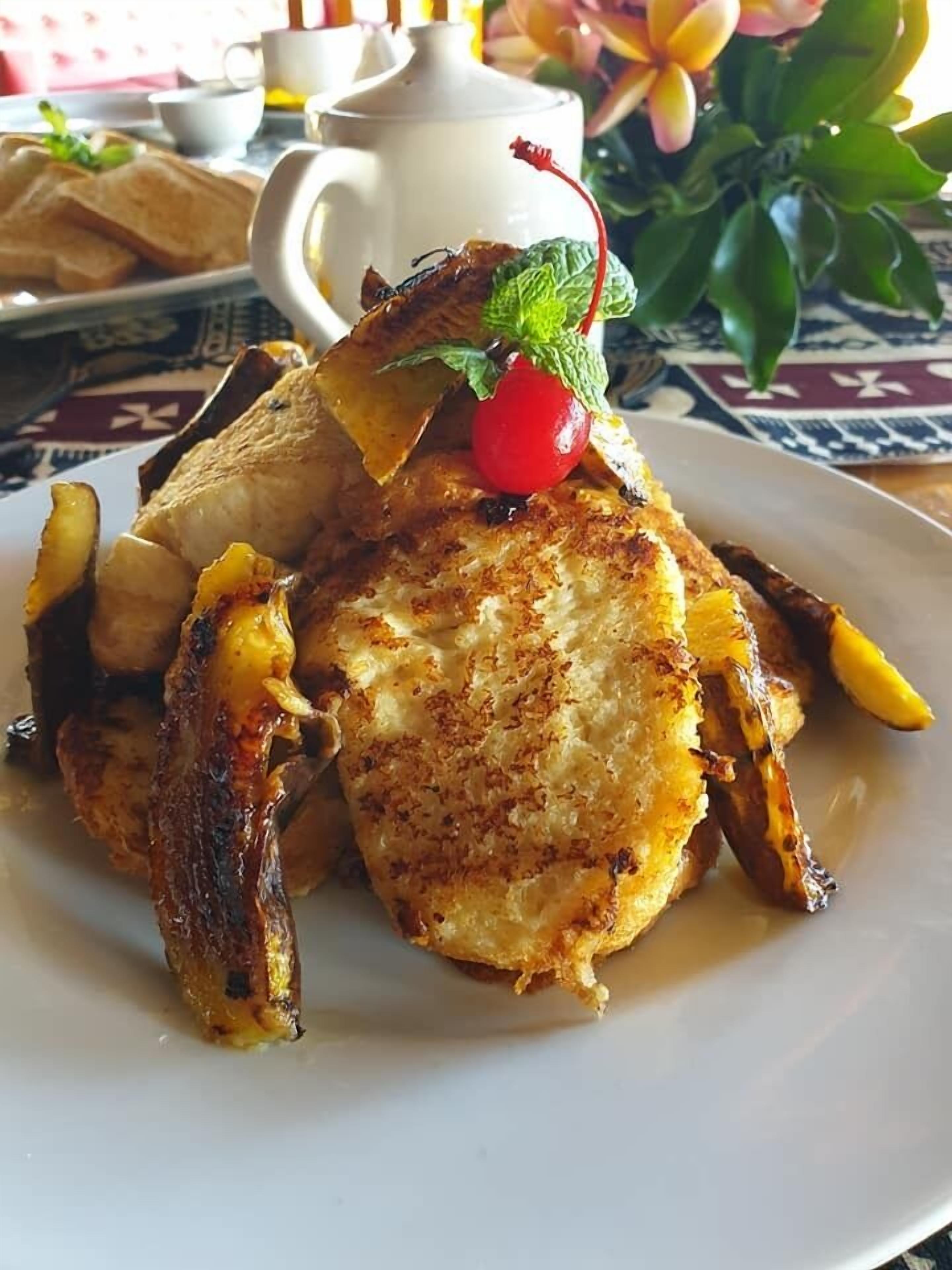 A plate of food with a teapot and a flower in the background.