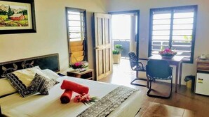 Habitación de hotel con cama, escritorio, silla y un refrigerador pequeño.