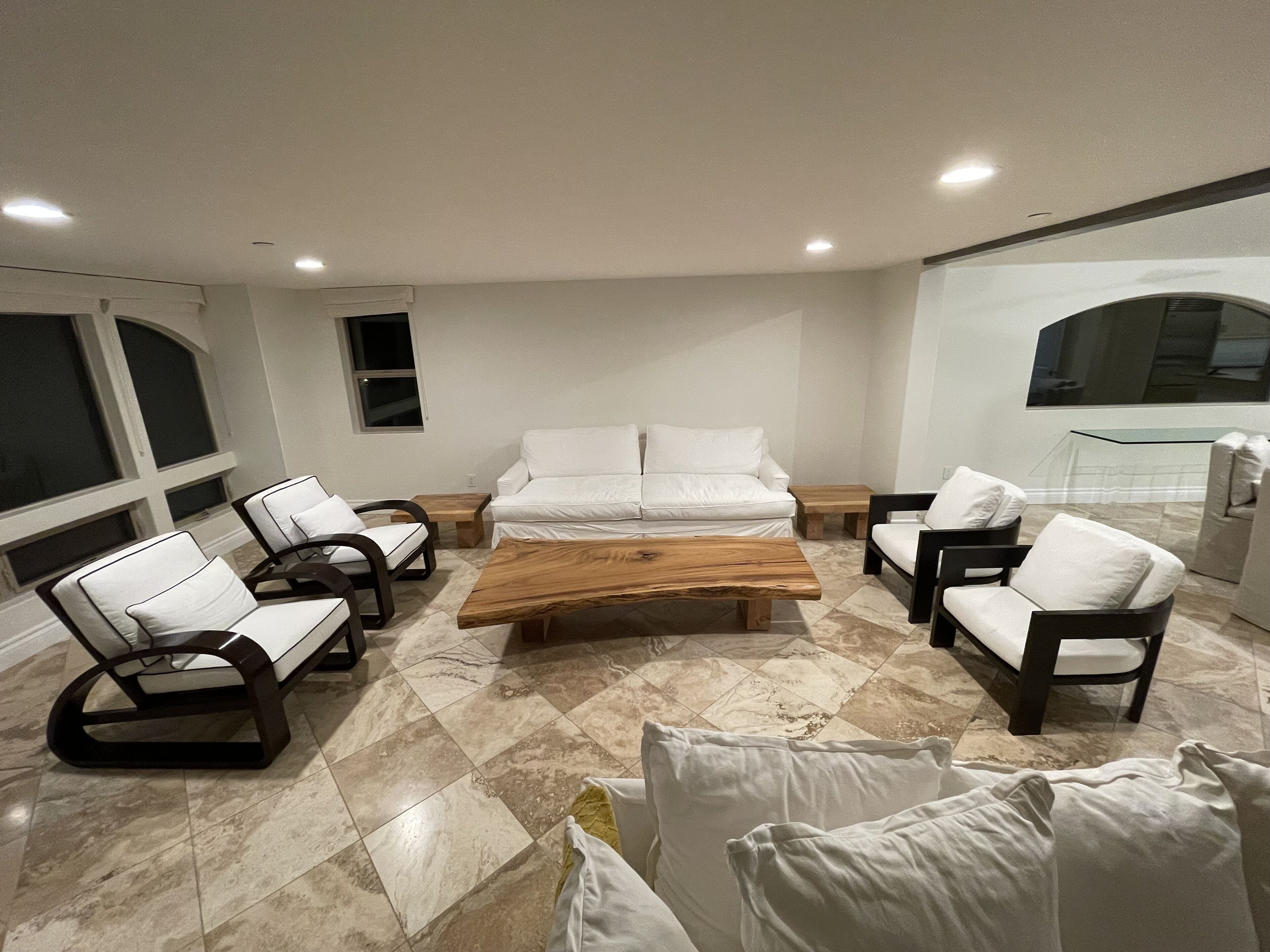 Een moderne woonkamer met een centrale salontafel, witte banken en fauteuils eromheen.