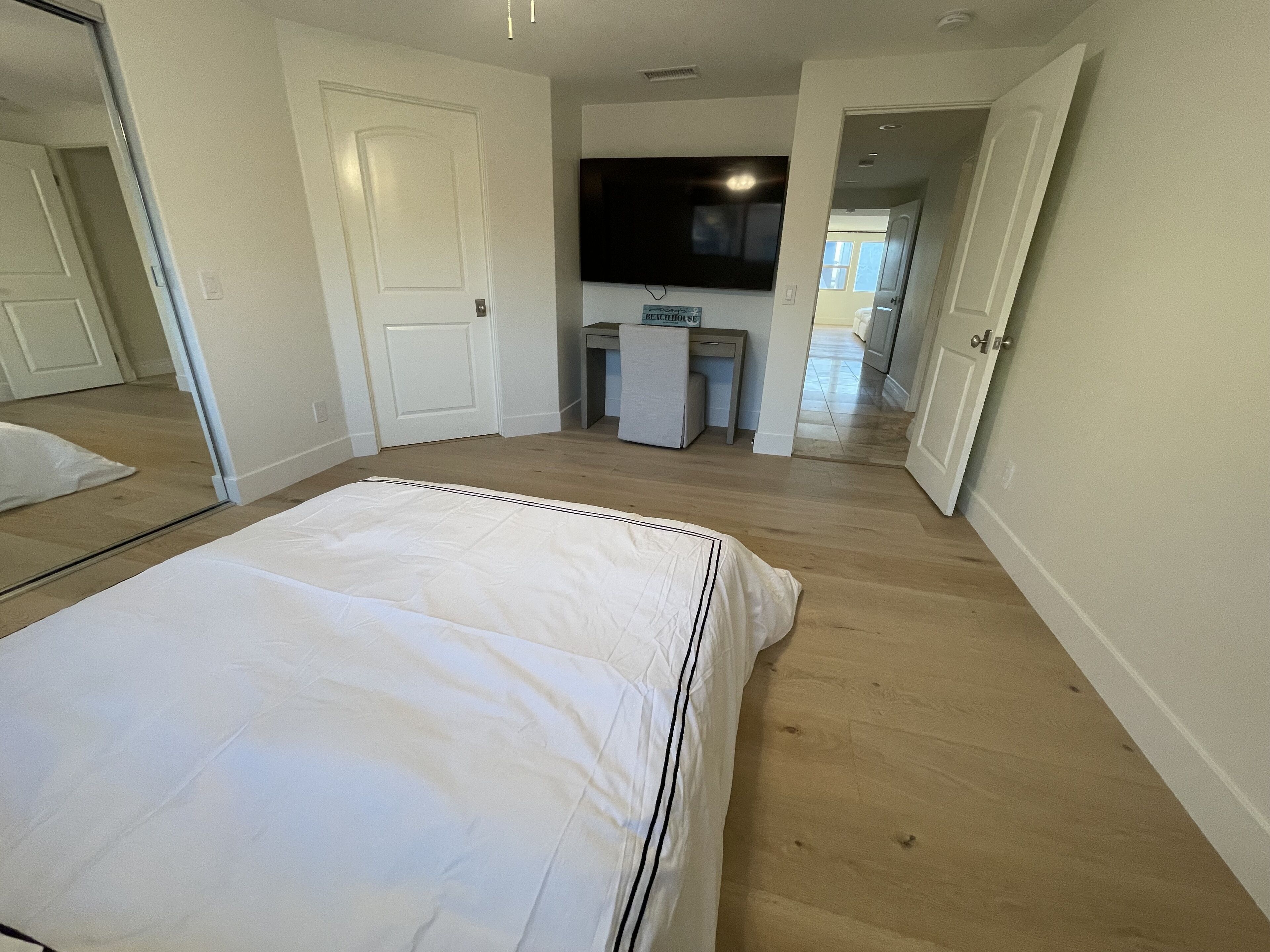 A bedroom with a bed, a TV mounted on the wall, and a desk.