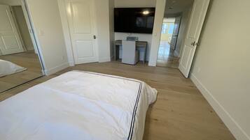 A bedroom with a bed, a TV mounted on the wall, and a desk.