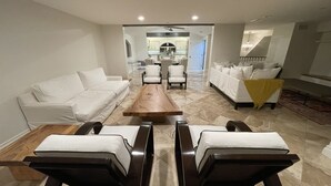 Una sala de estar moderna con un sofá blanco, una mesa de centro de madera y dos sillones.