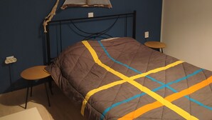 Ein Einzelbett mit brauner Bettdecke, einem Kopfteil, zwei Nachttischen und einer Deckenleuchte.