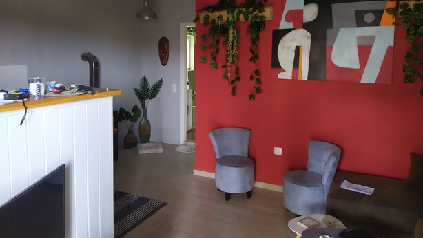 Ein Wohnzimmer mit roter Akzentwand, zwei grauen Sesseln, einem weißen Kamin und einem Holztisch.