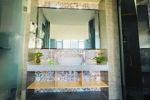 Un baño con un espejo grande, un lavabo blanco y una zona de ducha.