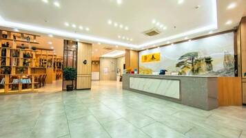 A hotel lobby with a reception desk, seating area, and a large wall mural.