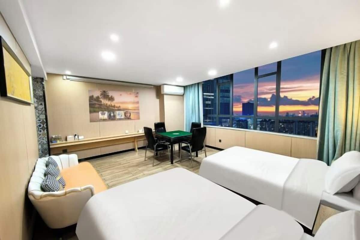 Habitación de hotel con dos camas, un escritorio y una mesa verde.