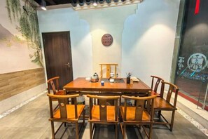 A dining area with a wooden table and chairs, a door, and a wall with a circular emblem. - Danzhou Guanlan Shangpin International Hotel (Danzhou)