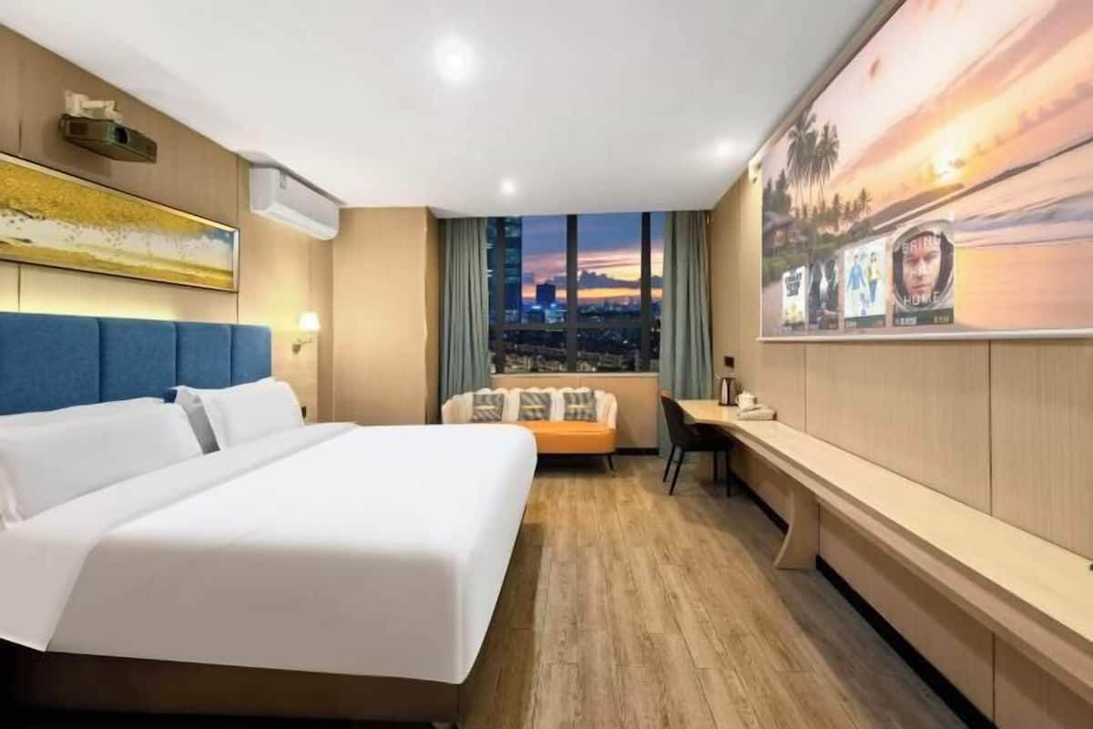 Habitación de hotel con una cama grande, un escritorio, un sofá y vistas a la ciudad desde la ventana.
