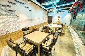 Un salón de conferencias con una mesa redonda y sillas de cuero, una pared de ladrillo y un mural.